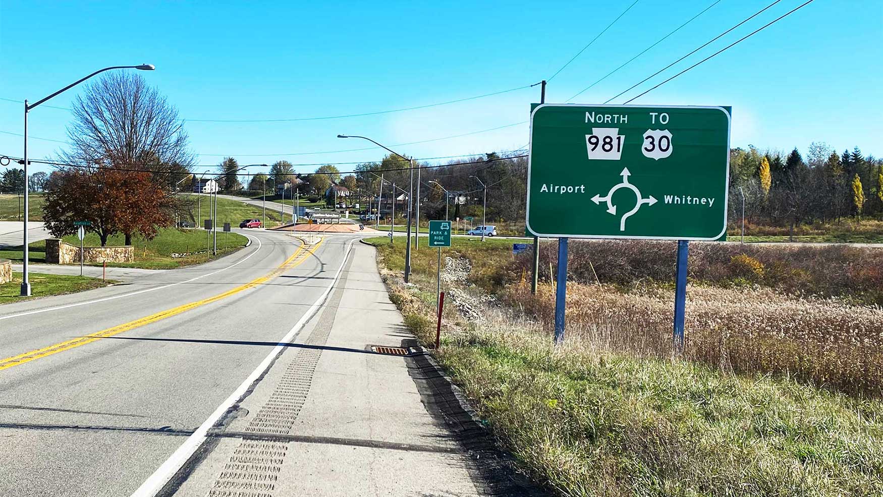 A green sign with directions for routes and a visual representation of the roundabout exits
